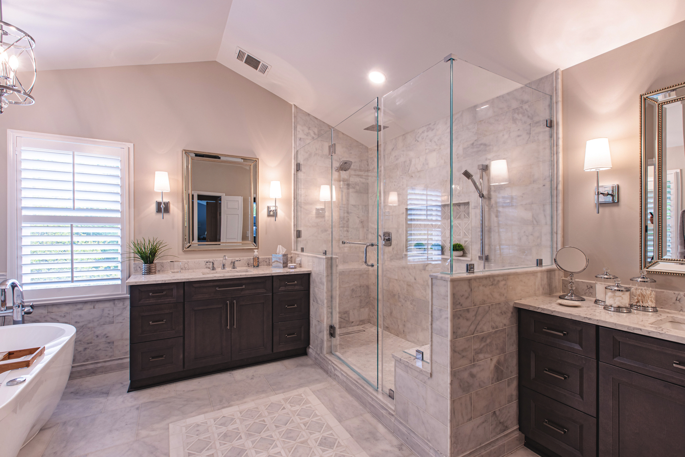 Elegant bathroom with 2 traditional brown vanities, an enclosed shower, and a bath tub